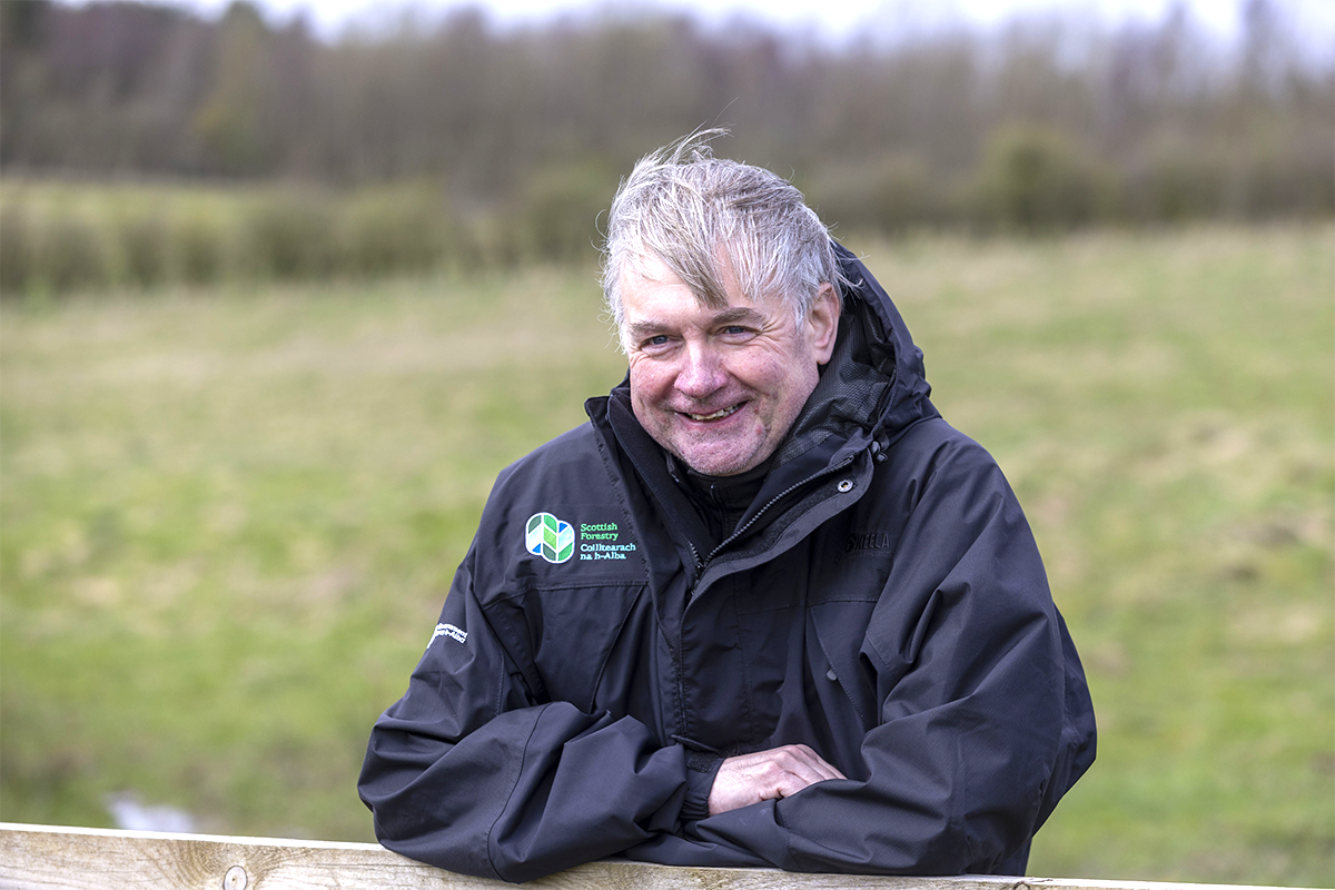 Paul Lowe, Chief Executive Officer of Scottish Forestry, leaning on a fence and smiling at camera.
